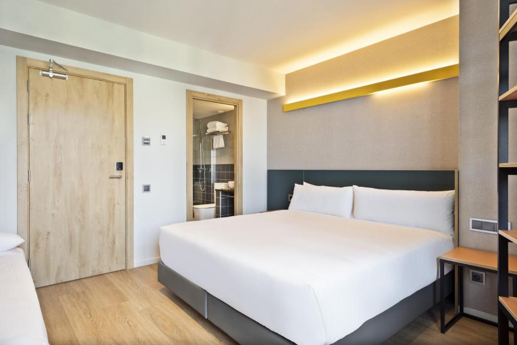 - une chambre avec un grand lit blanc et une porte dans l'établissement Hotel Brick Barcelona, à Barcelone