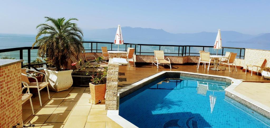 a swimming pool on top of a building with a balcony at Hotel Jangada Flat in Caraguatatuba