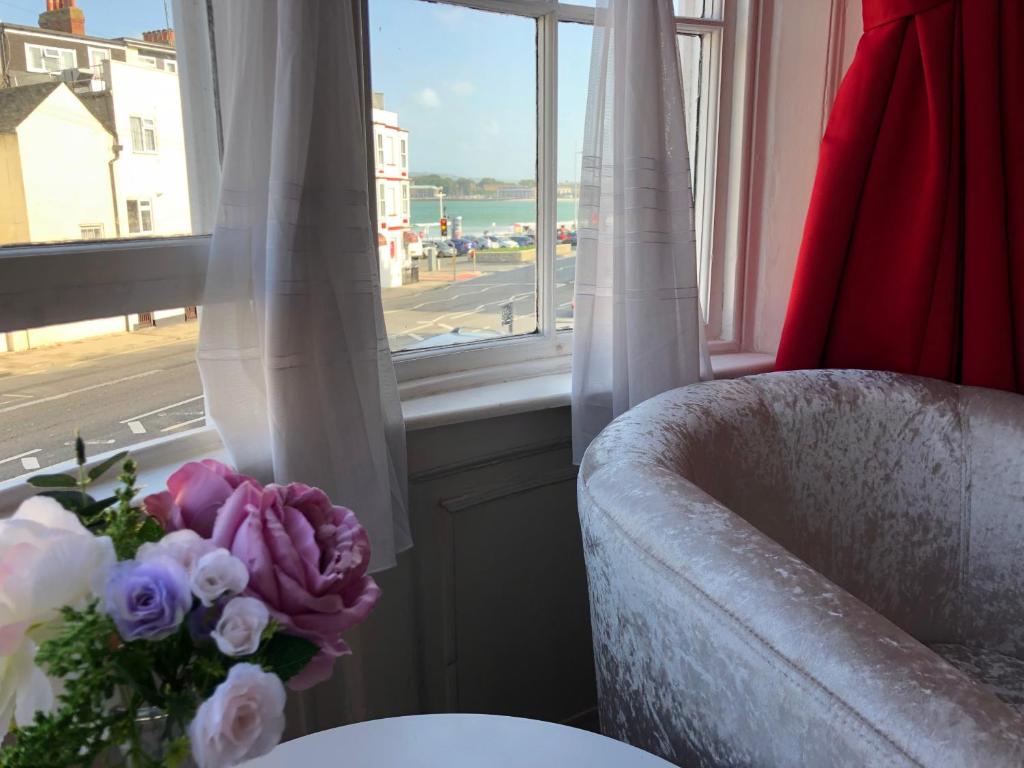 un vase de fleurs assis sur une table à côté d'une fenêtre dans l'établissement Beachcomber Guesthouse, à Weymouth