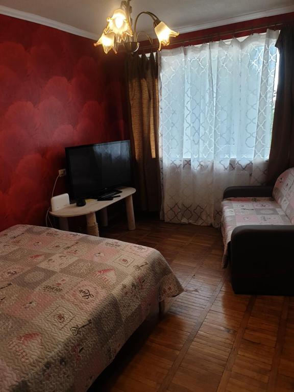 a bedroom with two beds and a tv and a window at Rose apartaments in Liepāja