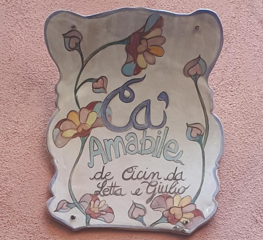 a sign hanging on a wall with flowers on it at CA AMABILE in Badalucco