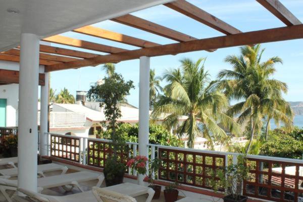 a porch with a view of the beach and palm trees at LALORA Hotel & Villas in San Patricio Melaque