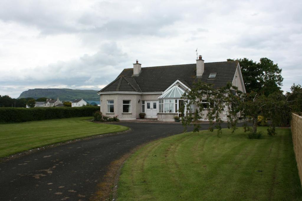 una casa blanca con techo negro en una carretera en Carrowbruagh en Limavady