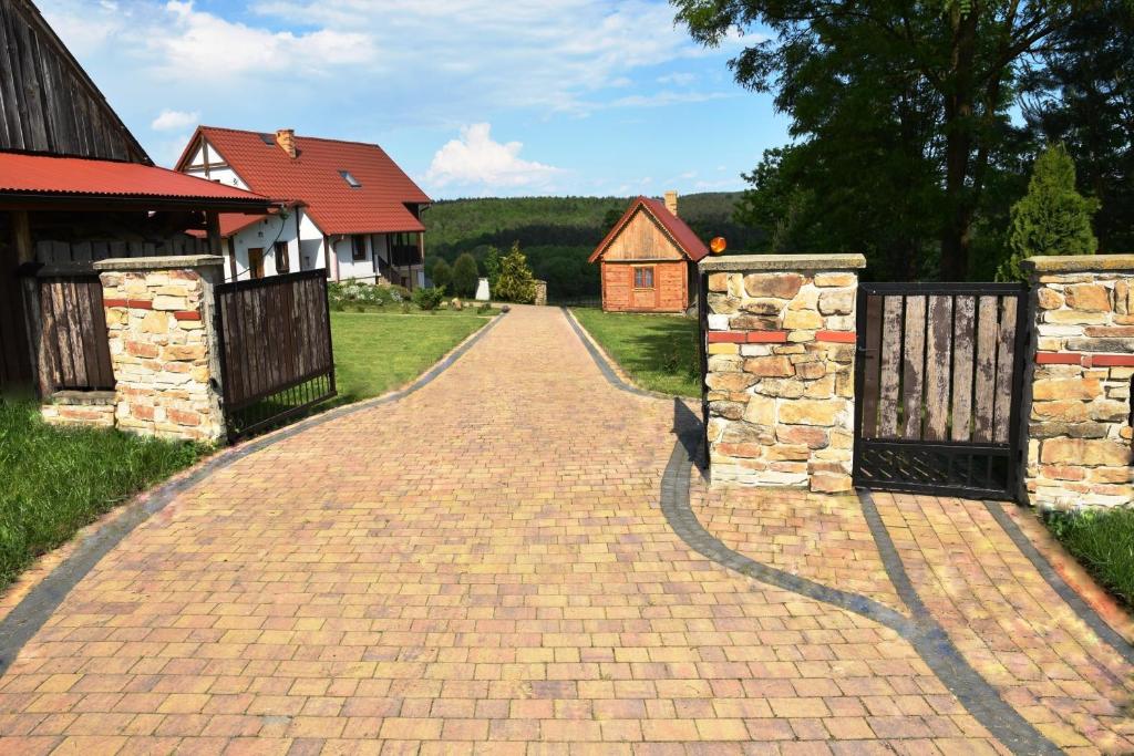 a brick driveway with two gates in front of a house at Drewniany domek z piernika in Iwaniska