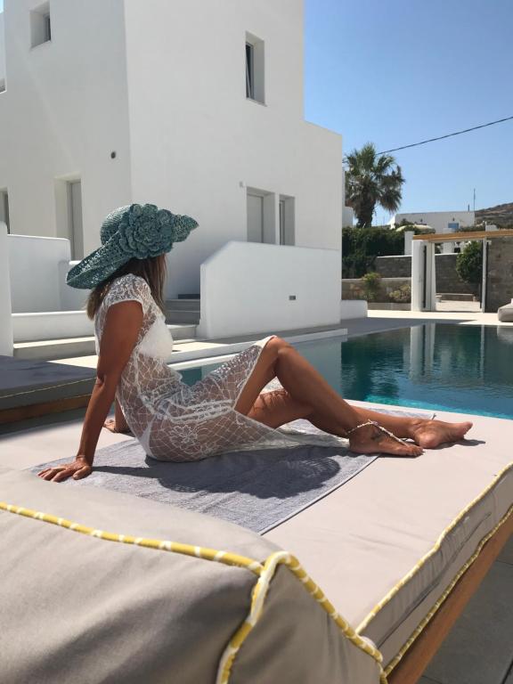 a woman sitting on a bed next to a swimming pool at Quartano Luxury Cycladic Residence, Adults Only (13+) in Naousa