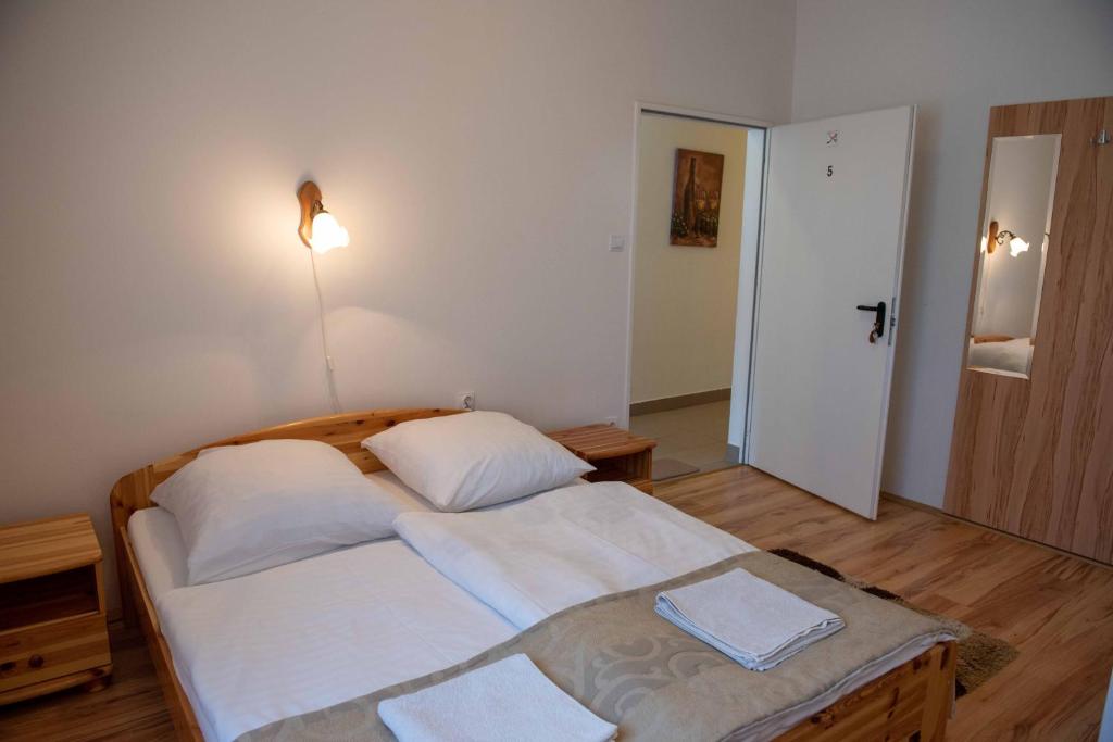 a bedroom with a bed with white sheets and a lamp at Anna Vendégház Tarcal in Tarcal