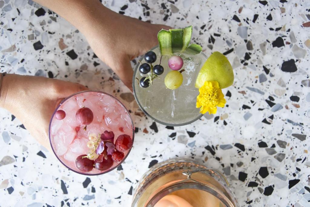 a person holding a drink with fruit on a table at Hotel Villa Rosa Riviera in Rimini