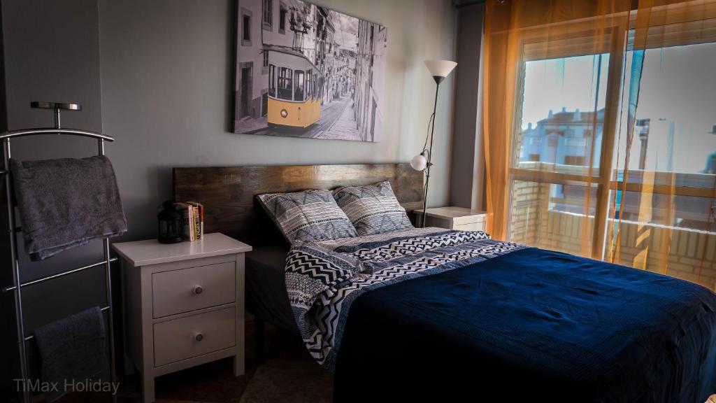 sypialnia z łóżkiem z niebieską kołdrą i oknem w obiekcie Timax Home Costa del Sol w mieście Caleta De Velez