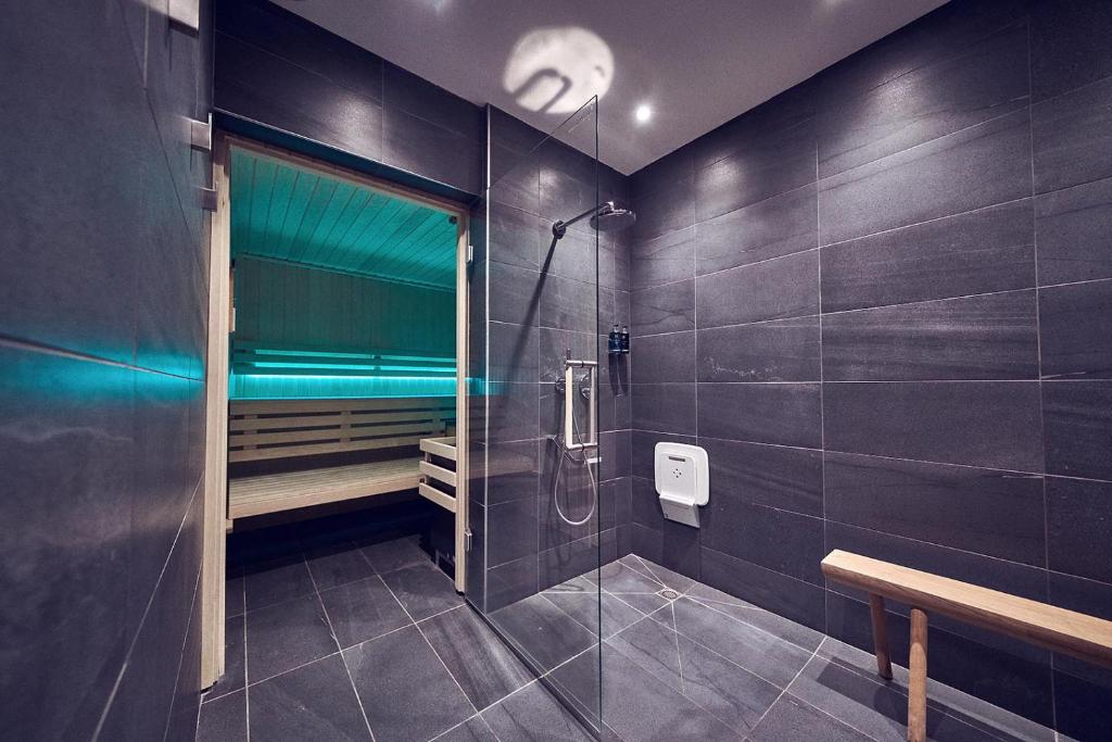 a bathroom with a walk in shower and a bench at Maison Nô - Hôtel et Rooftop in Lyon
