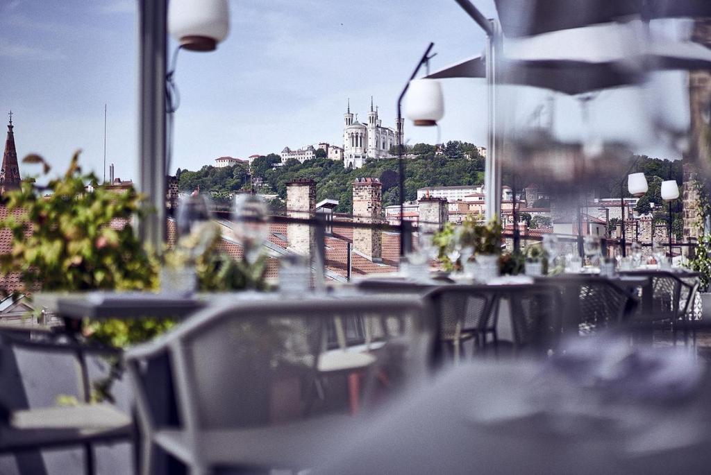 a view of a city from a restaurant with tables and chairs at Maison Nô - Hôtel et Rooftop in Lyon