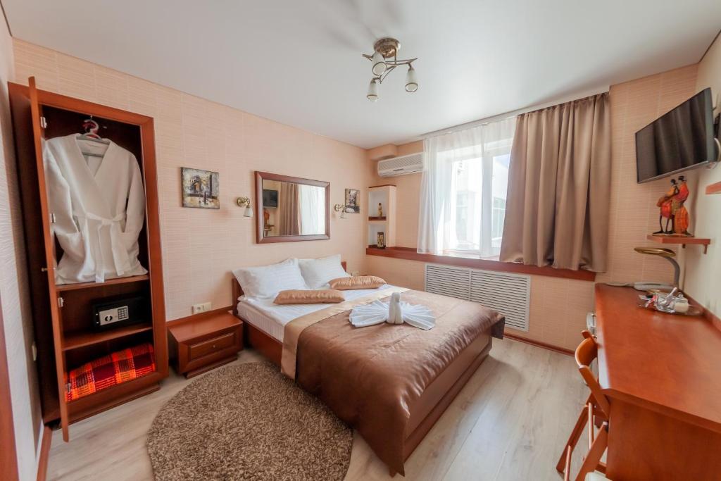 a bedroom with a bed and a dresser and a tv at City Hotel in Gomel