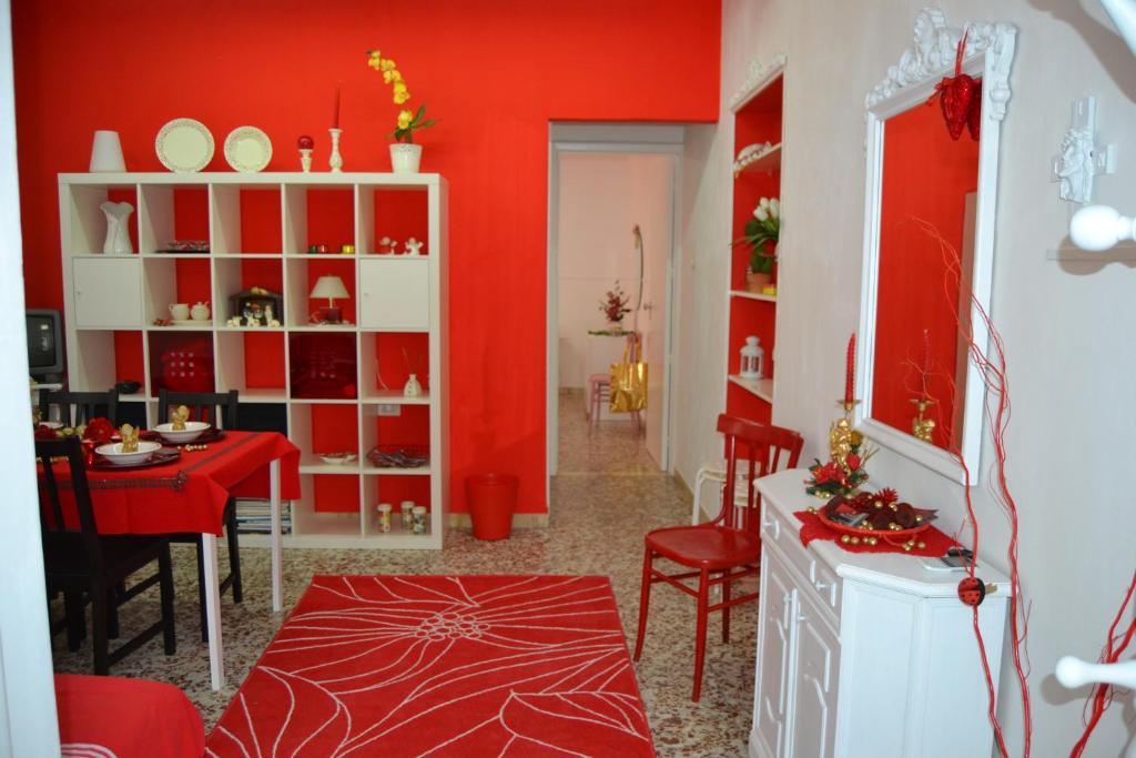 un soggiorno con pareti rosse, tavolo e sedie di Casa Vacanze Montalbano a Scicli
