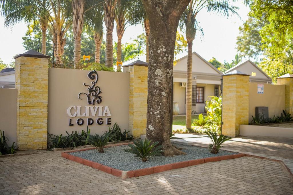 a sign for a villa lodge with trees in the background at Clivia Lodge in Louis Trichardt
