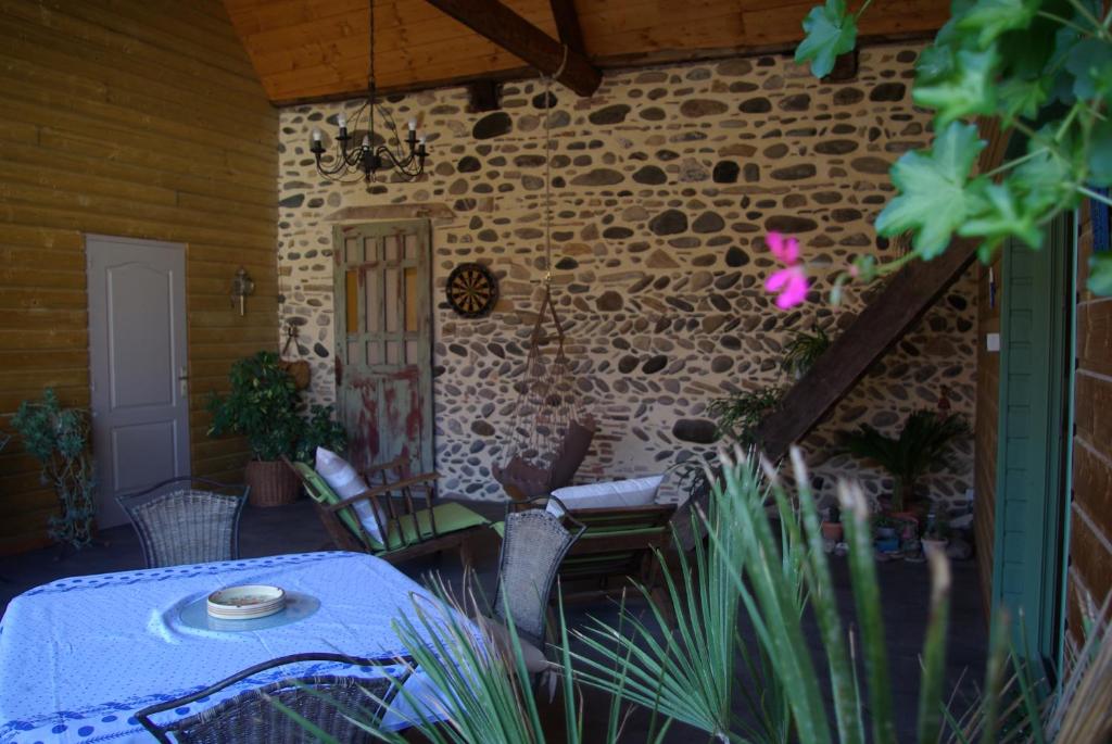 eine Terrasse mit einem Tisch, Stühlen und einer Ziegelwand in der Unterkunft Le gite du Poisson Roy in Navarrenx