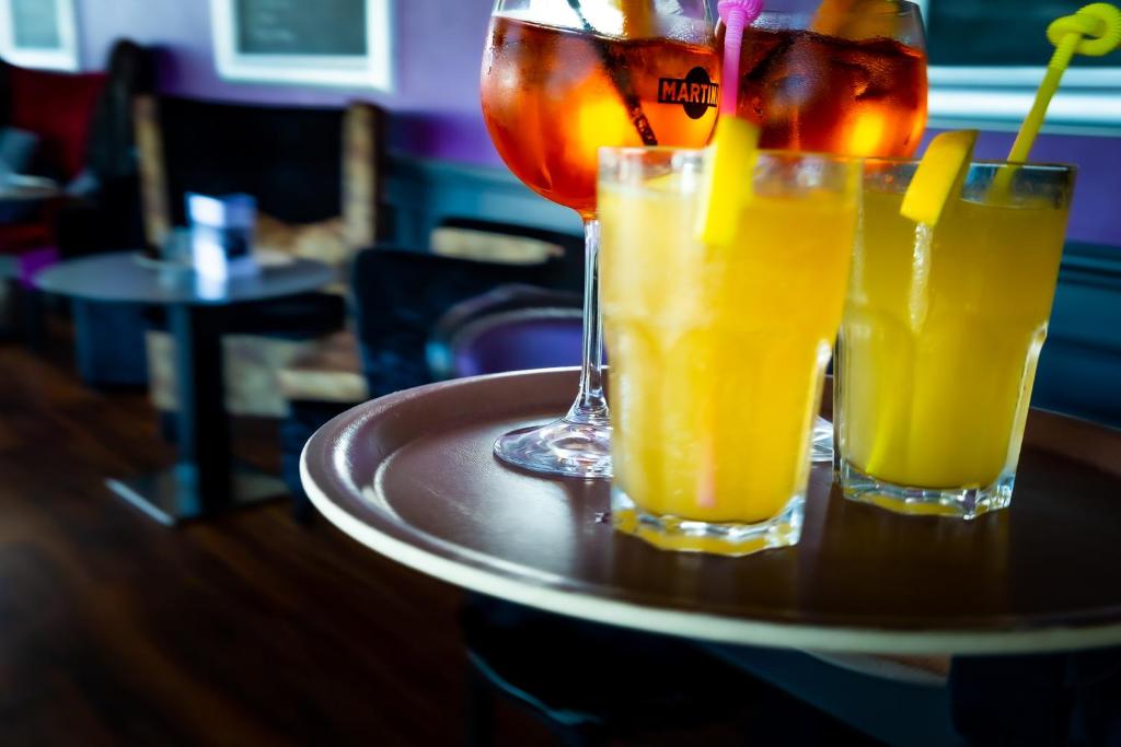 three glasses of orange juice on a table at La Villa Andry in Ouistreham