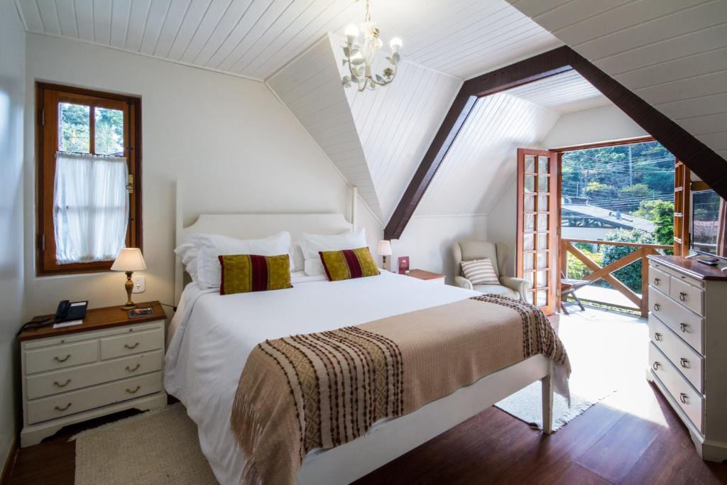 ein Schlafzimmer mit einem weißen Bett und einem großen Fenster in der Unterkunft Pousada Da Pedra in Campos do Jordão
