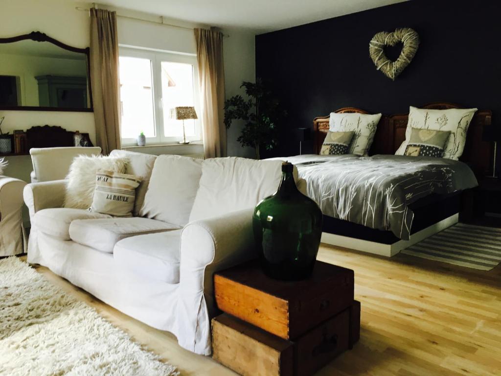 ein Wohnzimmer mit einem weißen Sofa und einem Bett in der Unterkunft Gästehaus Sellemols Ferienwohnung Korbmacher in Heuchelheim-Klingen