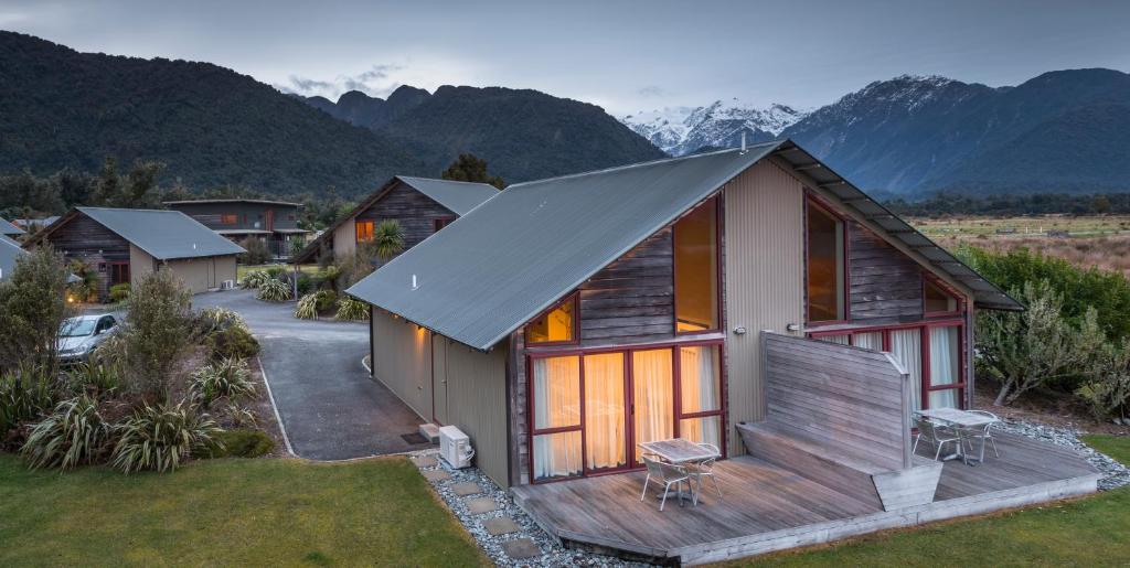 a house with a deck with mountains in the background at Glenfern Villas in Franz Josef