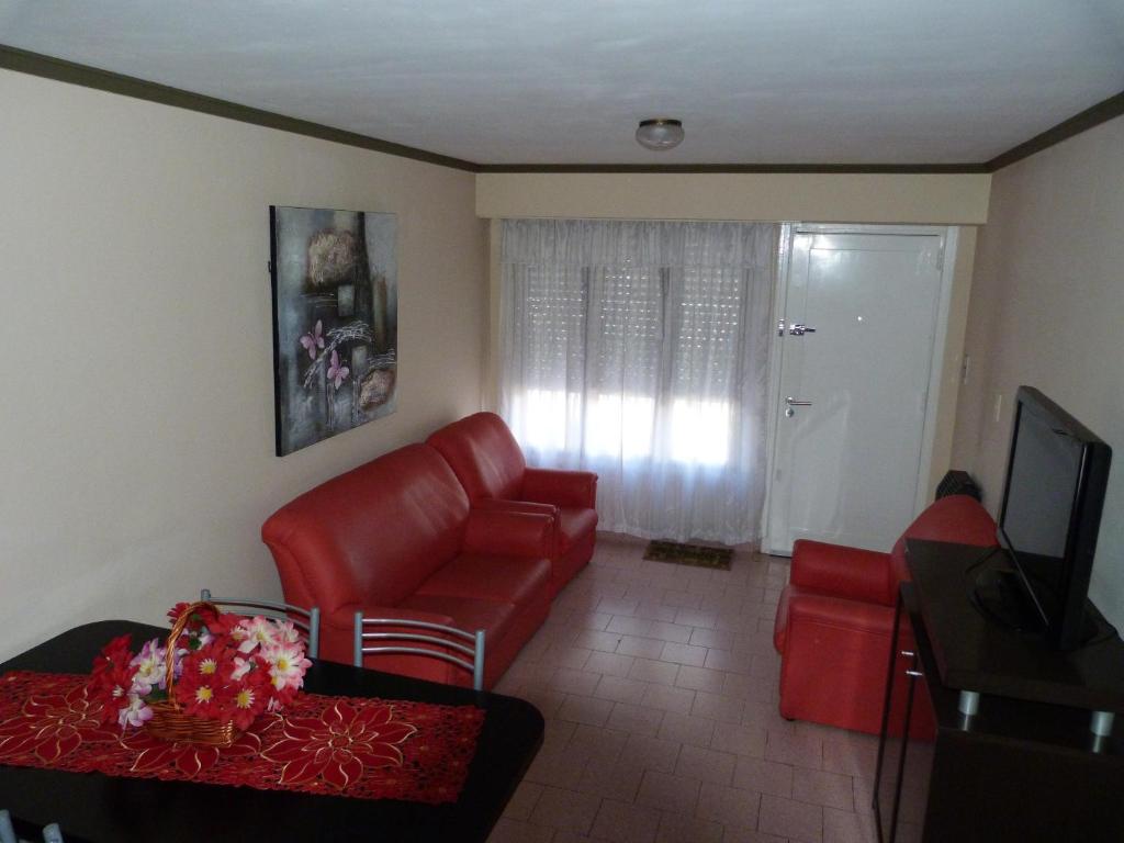 een woonkamer met een rode bank en een tv bij Departamento Maru in Tandil