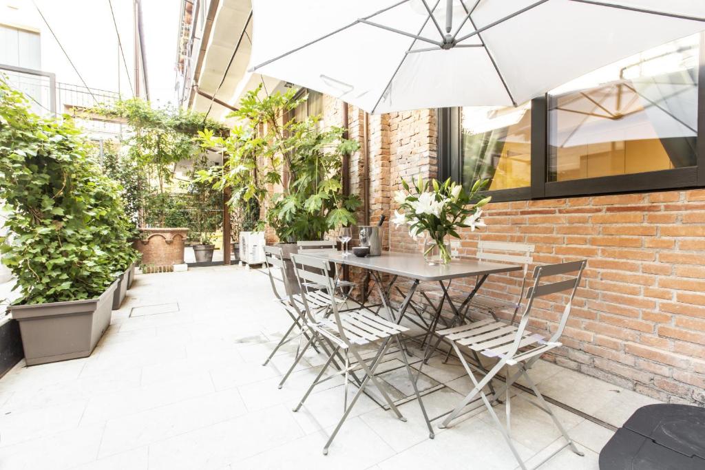 a table and chairs on a patio with plants at Elegant Fornasa Vecia, canal view with a beautiful garden R&R in Venice