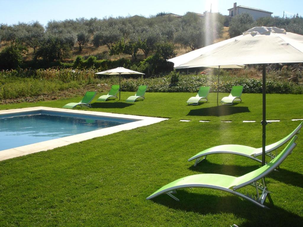 um grupo de cadeiras de jardim e um guarda-sol ao lado de uma piscina em Quinta Rota d' Oliveira em Santa Maria de Émeres