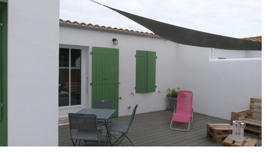 eine Terrasse mit zwei grünen Rollläden sowie einem Tisch und Stühlen in der Unterkunft le Paradis in La Noue