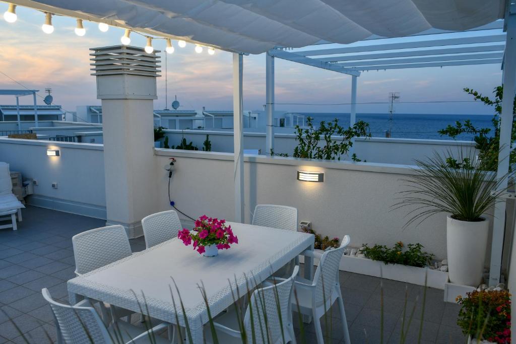 une table blanche et des chaises sur un balcon avec l'océan dans l'établissement Dimora Punta Azzurra, à Polignano a Mare