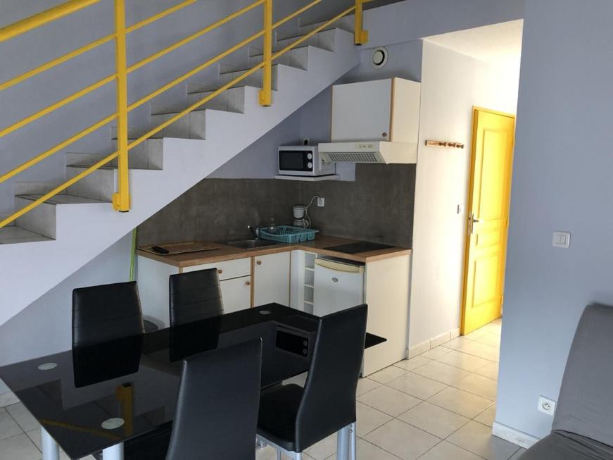 a kitchen with a table and chairs and a staircase at Appart Hotel Acadien in Salon-de-Provence