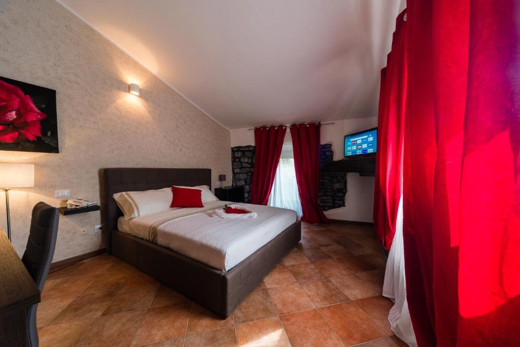 a bedroom with a bed with red curtains and a television at Le Undici Rose Hotel in Viterbo