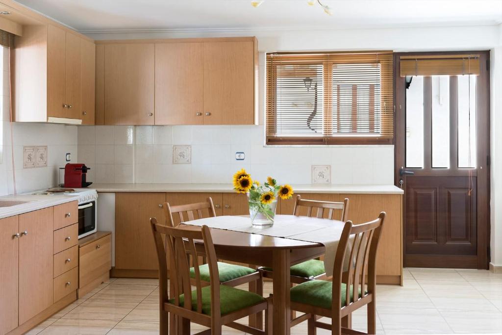 a kitchen with a table with chairs and a vase of flowers on it at Apartment in Peania (15min from Airport) in Paianía