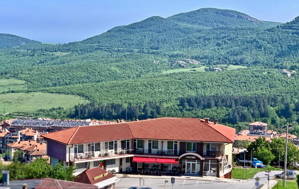 a building with a red roof in front of a mountain at Hotel Fort o Bel in Belogradchik