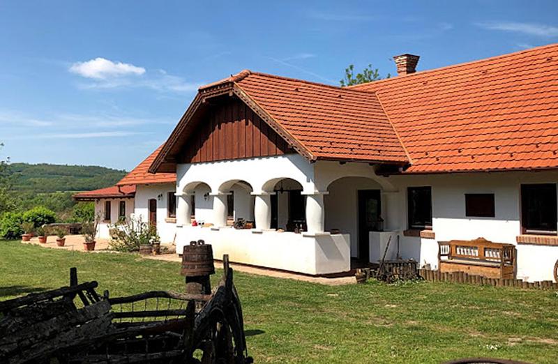 a white house with an orange roof on a field at Greenhouse in Szólád