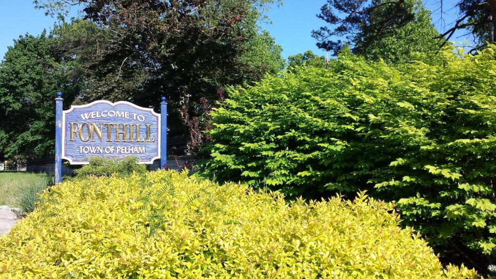 ein Schild für ein Hotel mit einigen Büschen in der Unterkunft Hipwell's Motel in Fonthill