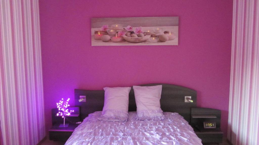ein lila Schlafzimmer mit einem Bett mit einer lila Wand in der Unterkunft Les Glycines in Choloy