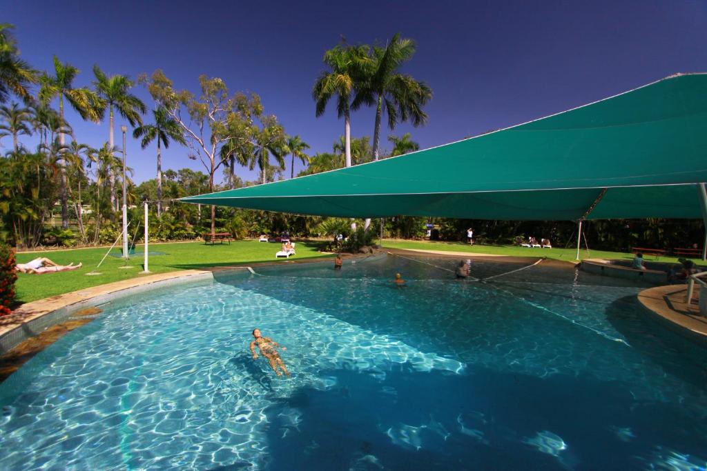 
a swimming pool with a pool umbrella in the middle of the pool at Aurora Kakadu Lodge in Jabiru
