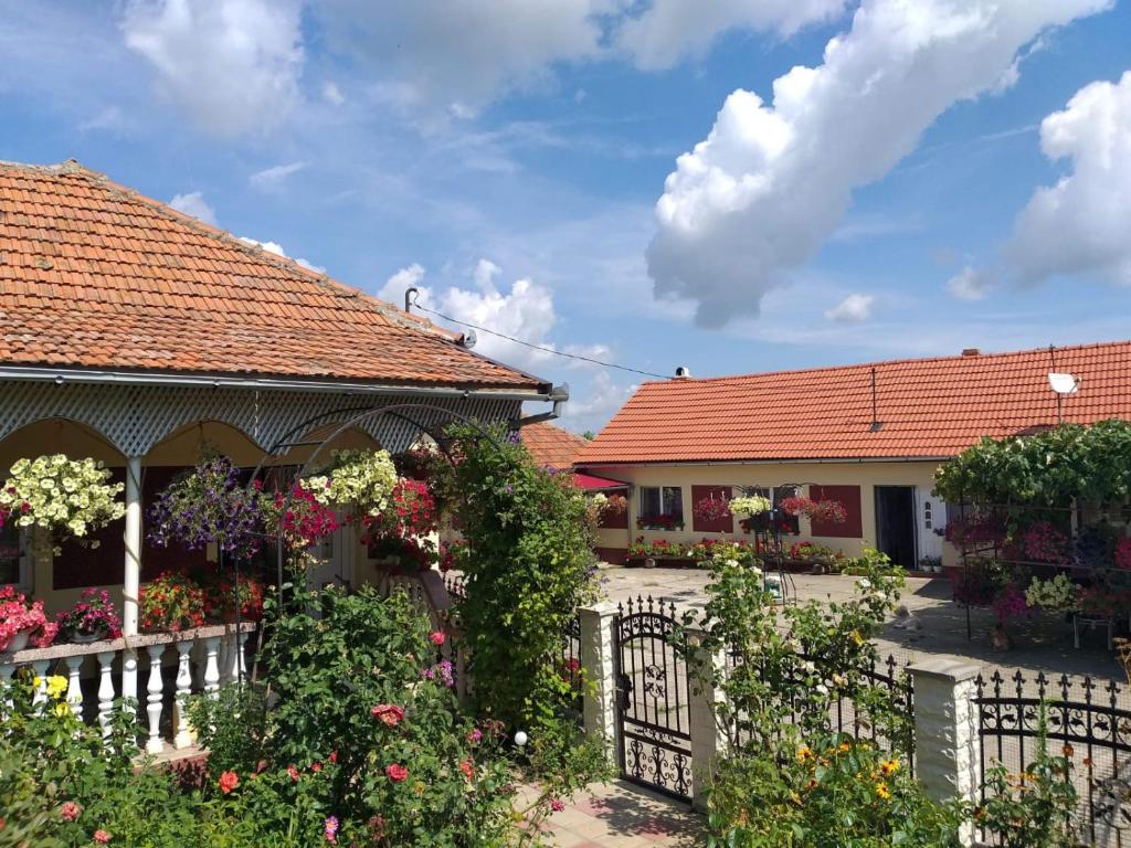 a white fence in front of two houses with flowers at La Mosu-n Retezat in Nucşoara