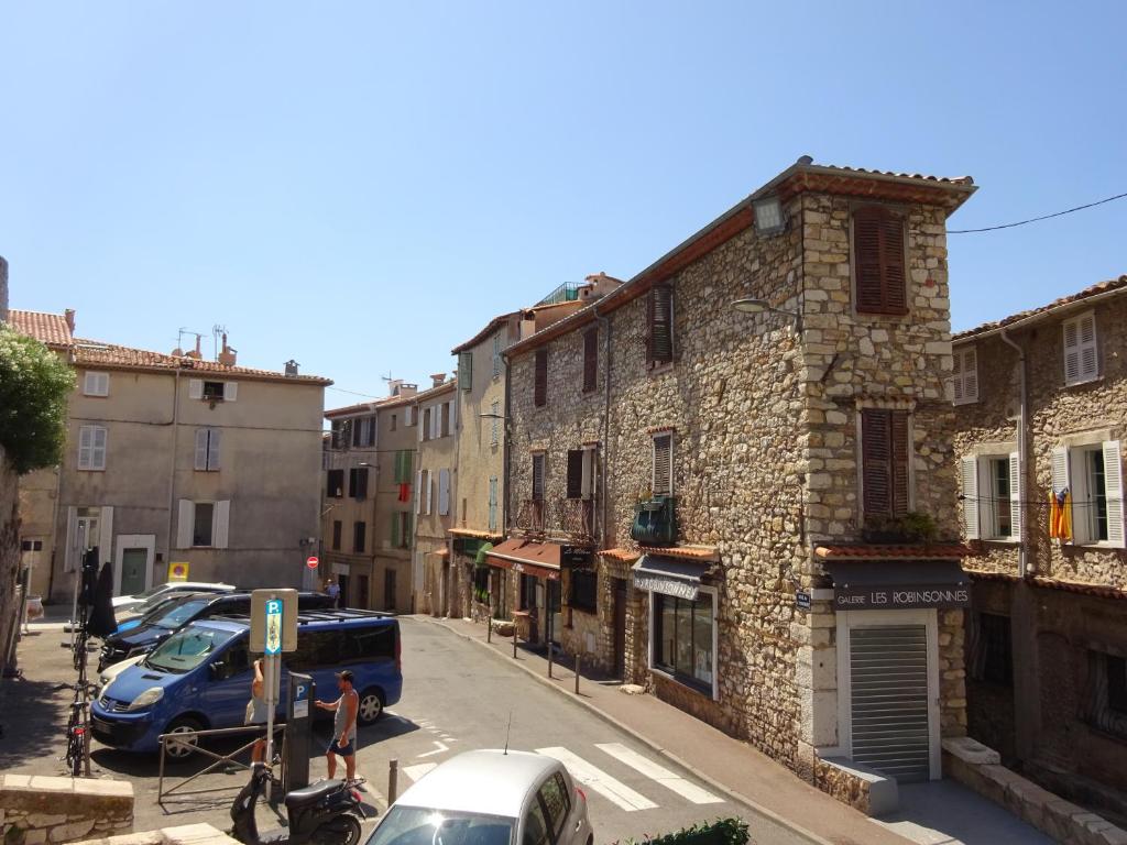 un antiguo edificio de piedra en una calle de la ciudad con coches en 6 rue de la tourraque, en Antibes