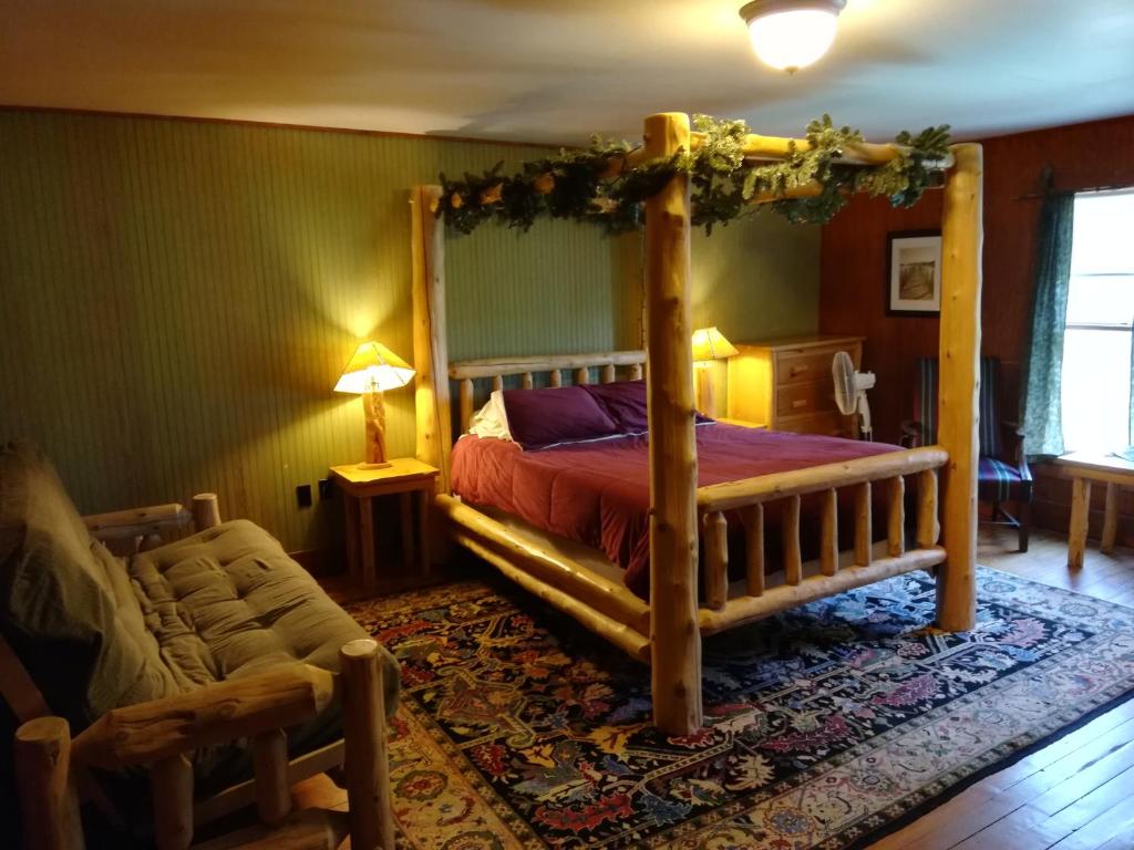 ein Schlafzimmer mit einem Himmelbett und einem Stuhl in der Unterkunft The Woods Inn in Inlet