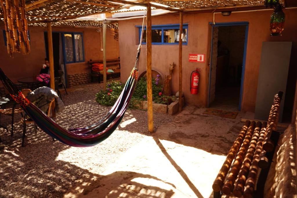 a patio area with chairs, a bench, and umbrellas at Hostal Mamatierra in San Pedro de Atacama