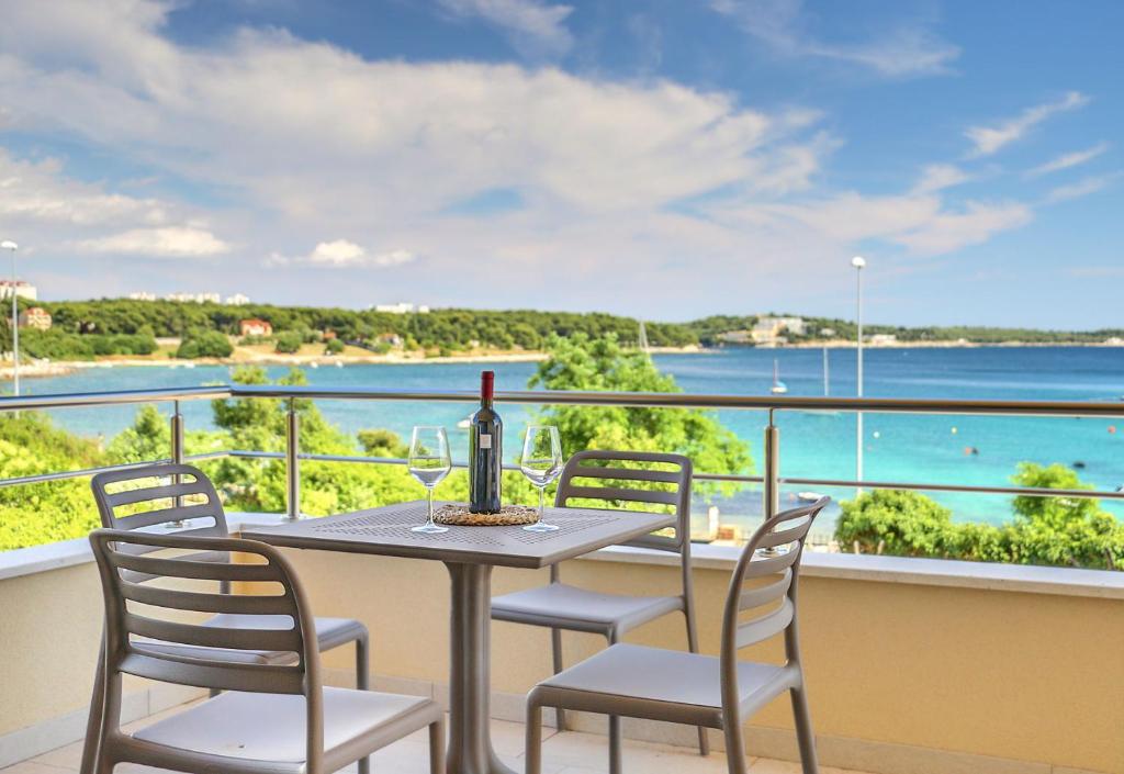 einen Tisch mit einer Flasche Wein und Stühlen auf dem Balkon in der Unterkunft Modo apartments in Pula