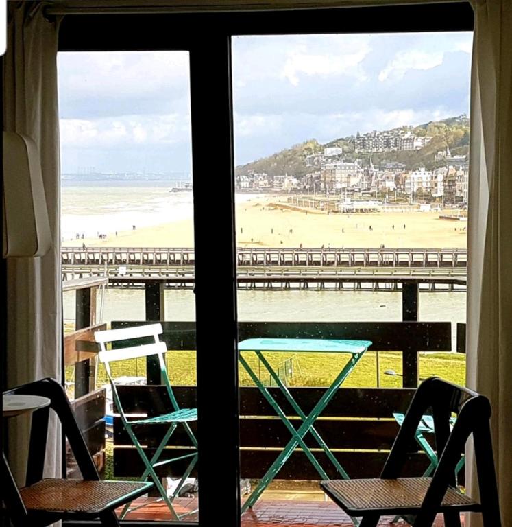 - une vue sur la plage depuis une fenêtre avec des chaises dans l'établissement Appartement de charme vue mer, à Deauville