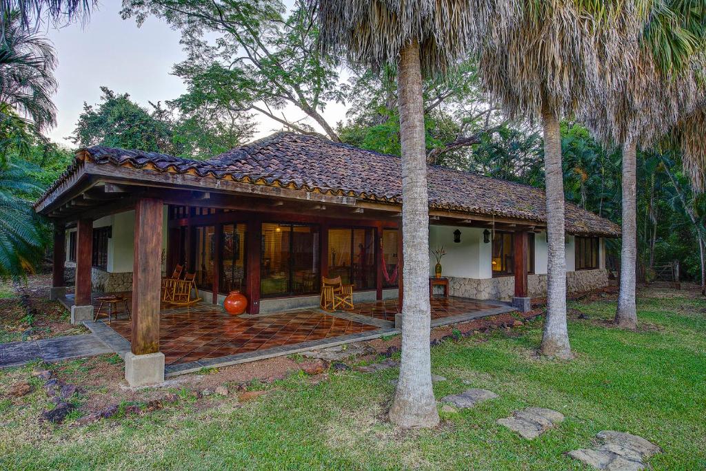 uma casa com um alpendre e duas palmeiras em Hotel Hacienda La Pacifica em Cañas