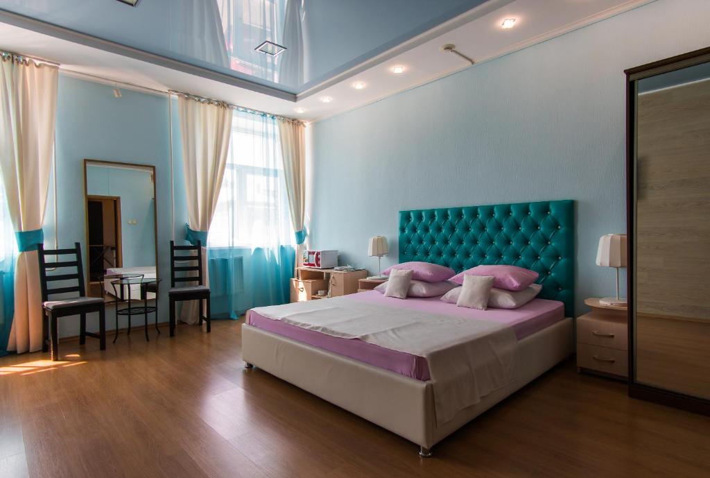 a bedroom with a large bed with a blue headboard at Гостиница Бизнес Турист in Barnaul