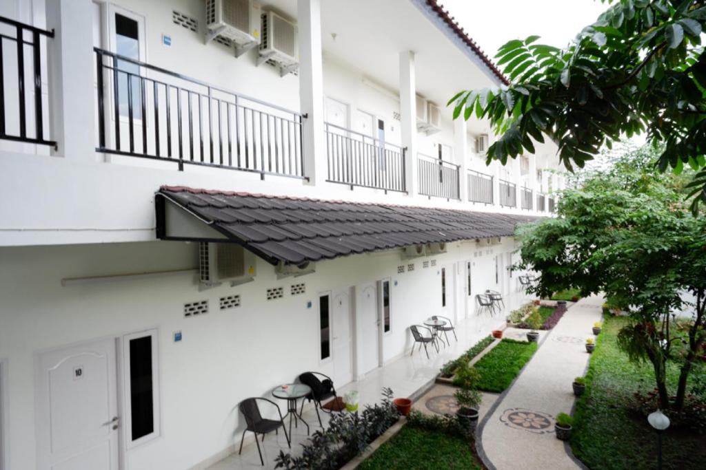 馬塔蘭的住宿－RedDoorz near Mataram University，公寓大楼设有带桌椅的庭院。