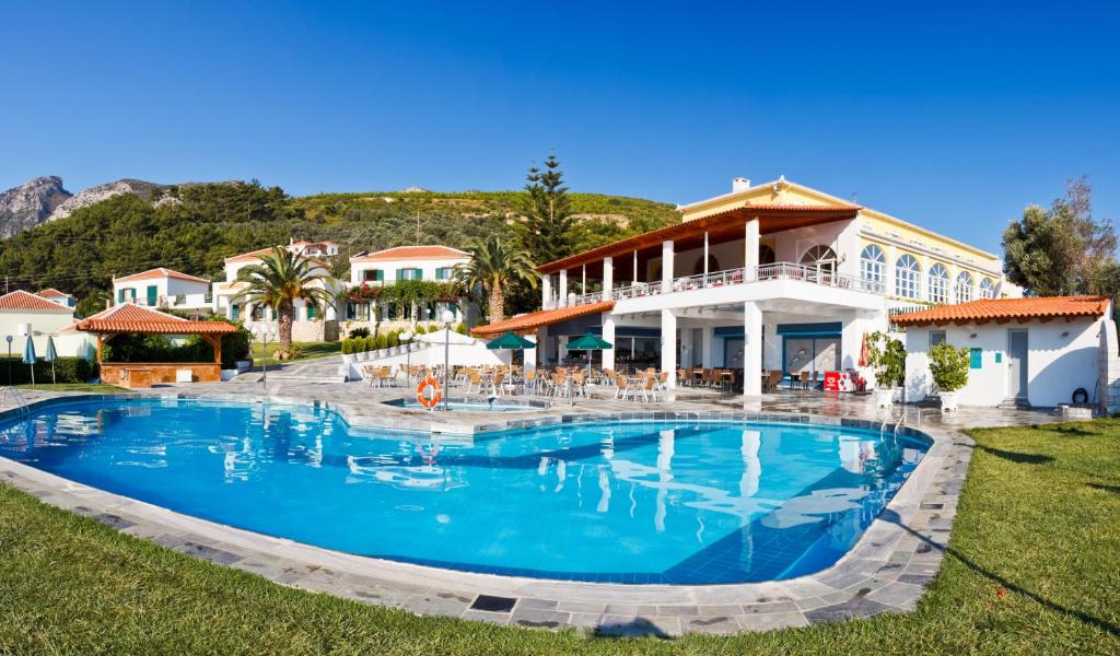 a large swimming pool in front of a house at Arion Hotel in Kokkari