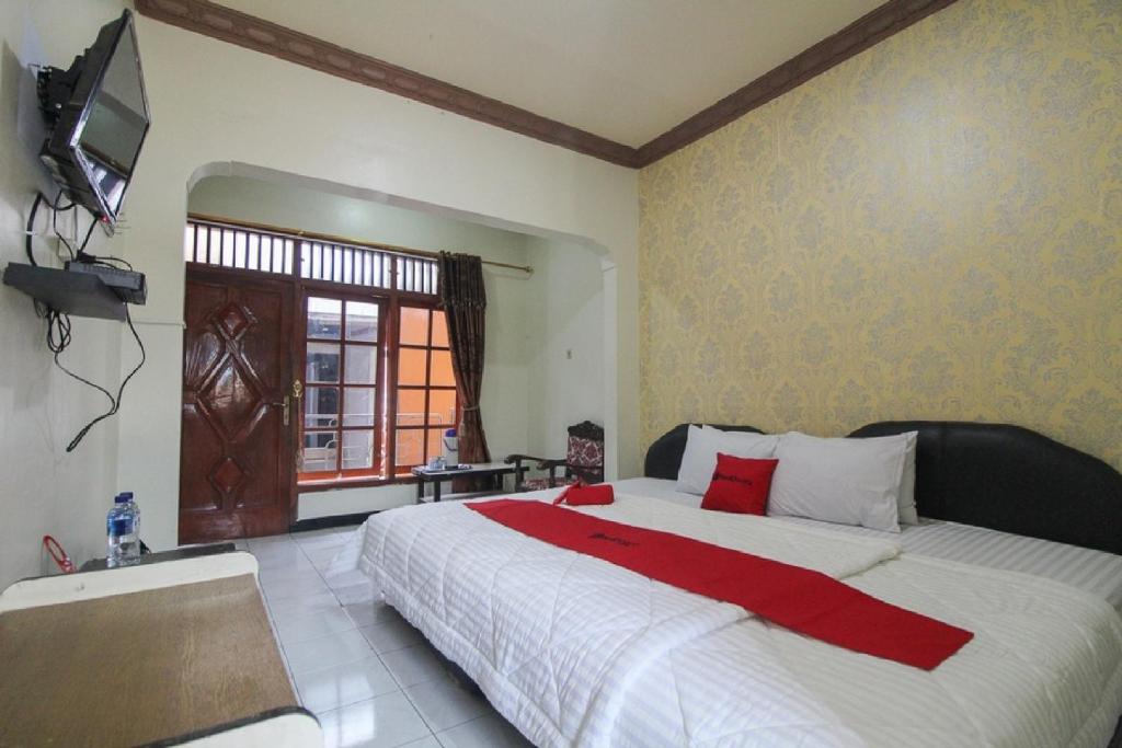 a bedroom with a large bed and a tv on the wall at RedDoorz near Sarangan Lake in Magetan