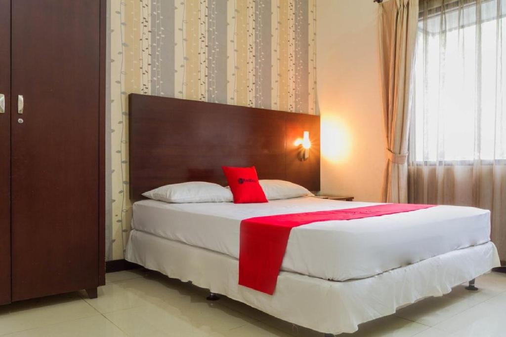 a bedroom with a large white bed with red pillows at RedDoorz @ Cikutra 3 in Bandung