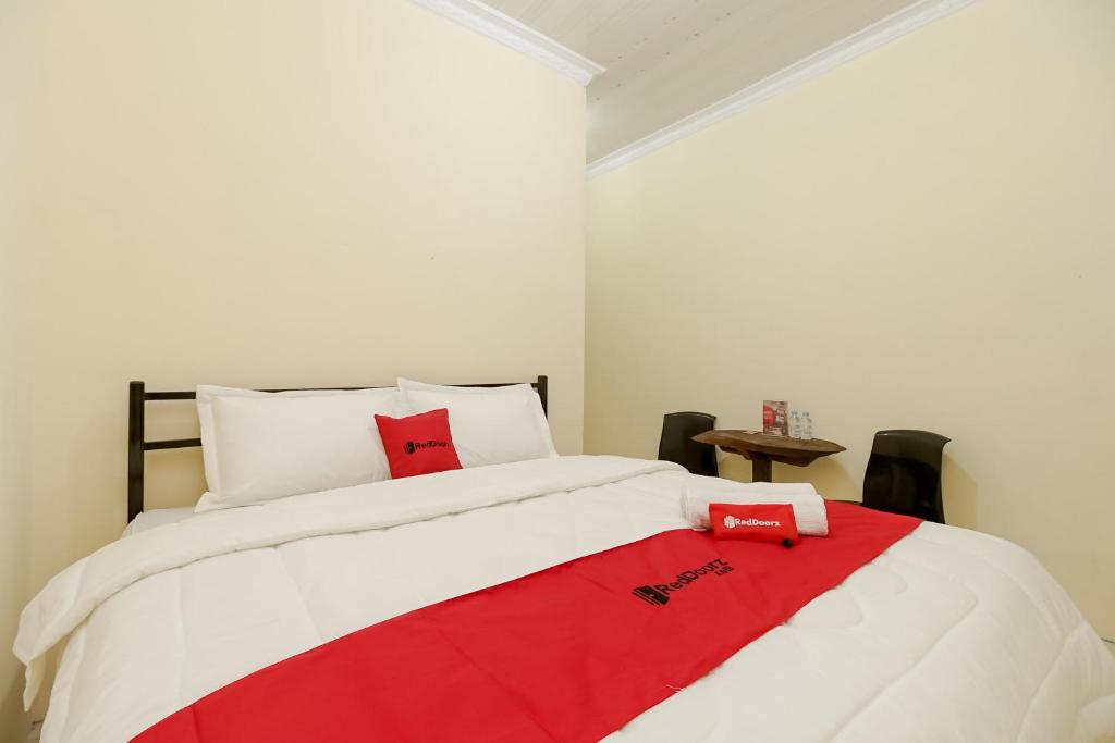 um quarto com uma cama com um cobertor vermelho em RedDoorz at Permata Ivana Berastagi em Berastagi