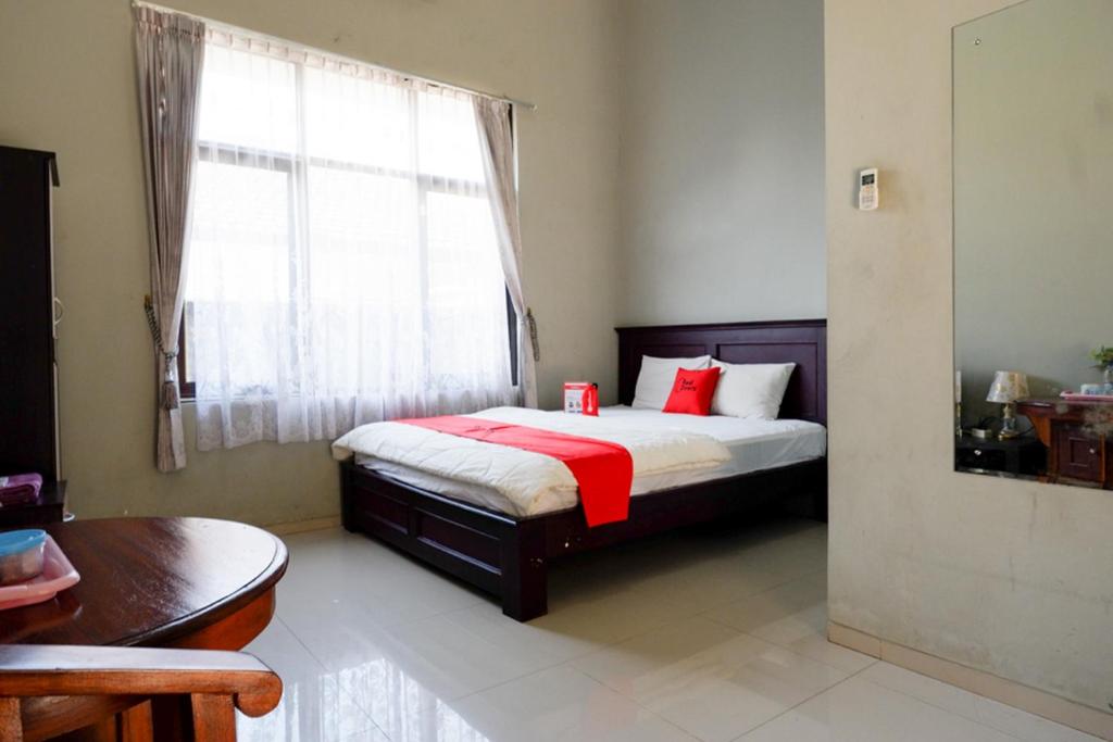 Un dormitorio con una cama con almohadas rojas y una ventana en RedDoorz Syariah near Menara Kudus en Kudus