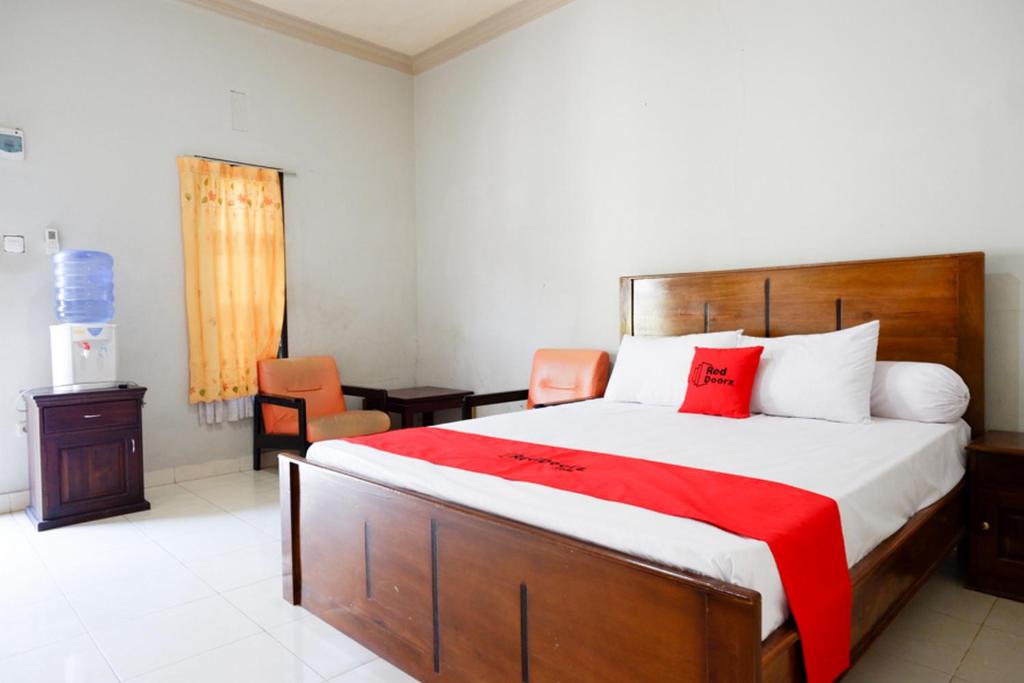 um quarto com uma cama grande e um cobertor vermelho em RedDoorz near Mutiara SIS Al Jufrie Airport Palu em Palu